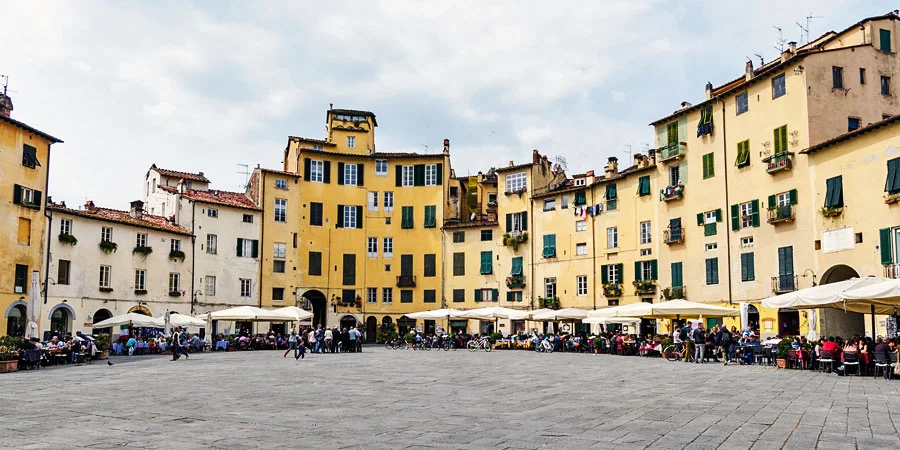 De Piazza dell'Anfiteatro in Lucca: een ovaal plein met gele huizen, groene luiken en terrasjes